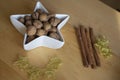 Christmas still life with walnuts in white bowl, golden thin wire stars and cinnamon bark decoration on wooden table Royalty Free Stock Photo