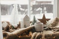 Christmas still life, winter hygge home. Warm cup of tea, christmas decor and lights at window