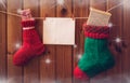 Christmas stockings and greeting card on wooden wall. Royalty Free Stock Photo