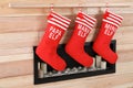 Christmas stockings hanging on wooden wall near decorative fireplace.