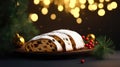 Christmas stollen with holly berries,fir branches and festive decorations on dark table with golden bokeh background.