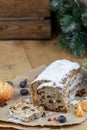 Christmas stollen with a mixture of dried fruits, nuts and powdered sugar on a board.