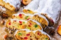 Christmas Stollen. Traditional Sweet Fruit Loaf with Icing Sugar on the parchment paper with hazelnuts, dry sliced apple, cinnamon