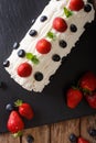 Christmas strawberry roll with whipped cream, mint and blueberries close-up on the table. Vertical top view Royalty Free Stock Photo