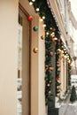 Christmas street decor. Stylish christmas fir branches with golden lights and colorful festive baubles in store window at holiday Royalty Free Stock Photo