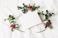 Christmas styled stock photo. festive greeting card, invitation mockup scene. Still life with paper card and holly