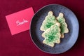 Christmas sugar cookies for Santa on a black plate, note to Santa, red fabric background