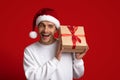 Christmas Surprise. Excited Young Man In Santa Hat Holding Wrapped Present Box Royalty Free Stock Photo