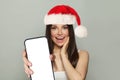 Christmas surprised brunette woman holding smartphone with empty blank display screen on white background Royalty Free Stock Photo