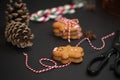 Christmas sweet gift concept: gingerman cookies, pinecones, candycane on black background with red-and-white string. Selective