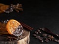 Christmas sweets, candied fruits in chocolate. Caramelized orange slices on a wooden stand, black stone background. Near spices