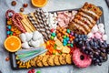 Christmas sweets platter. Christmas fruit cake, candy, chocolate, candy cane, cookies, fruit on black tray