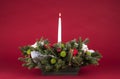 Christmas Table Arrangement or Centerpiece with flowers, evergreen branches and White Lit Candle Royalty Free Stock Photo