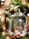 Christmas table decoration with deer figurine and trees inside the glass cloche with falling snow Royalty Free Stock Photo