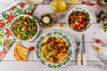 Christmas table. Green salad with strawberry and pasta rotini with tomato