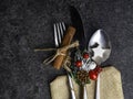 Christmas table place setting, cutlery in burlap bag with festive decorations star, cinnamon stick, pinecone with snow, berries,