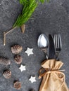 Christmas table place setting, cutlery in burlap bag with festive decorations star, golden bow, pinecone with snow, green branch