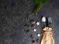 Christmas table place setting, cutlery in burlap bag with festive decorations star, golden bow, pinecone with snow, green branch