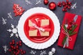 Christmas table place setting with empty red plate, cutlery with festive decorations star bow ball on stone background Royalty Free Stock Photo