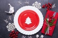 Christmas table place setting with empty red plate, cutlery with festive decorations star bow ball on stone background Royalty Free Stock Photo