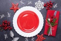 Christmas table place setting with empty red plate, cutlery with festive decorations star bow ball on stone background Royalty Free Stock Photo