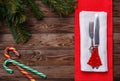 Christmas table place setting with fork and knife, decorated christmas toy - red fir-tree, two lollipop cane and christmas pine br Royalty Free Stock Photo