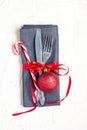 Christmas table place setting with knife, fork, red ball, candy cane and ribbon over white table with copyspace Royalty Free Stock Photo