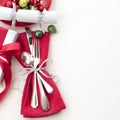 Christmas Table Place Setting in Red, White and Silver with Silverware, a gift, and party cracker on White Cloth Background with r