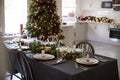 Christmas table setting with bauble name card holders arranged on plates and green and red decorations with Christmas tree and kit Royalty Free Stock Photo