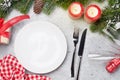 Christmas table setting with candles, champagne, gift box and fir tree branch covered by snow on stone background. Top view with Royalty Free Stock Photo