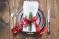 Christmas table setting with candy cane and red ribbon as decor, vintage dishware, silverware and decorations on wooden board. Royalty Free Stock Photo