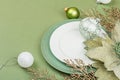 Christmas table setting with ceramic plates, traditional decor on Savannah Green color background