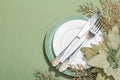 Christmas table setting with ceramic plates, traditional decor on Savannah Green color background