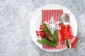 Christmas table setting with empty festive white plate and cutlery with Xmas decorations, snowflake, cone, Xmas tree branches Royalty Free Stock Photo