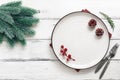 Christmas table setting. Empty white plate and spruce branch on a white wooden table. Top view, flat lay Royalty Free Stock Photo