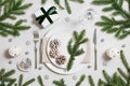 Christmas table setting with fir branches, gifts, silver decorations on white background. New Year\'s Eve dinner. Royalty Free Stock Photo