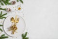 Christmas table setting with fir branches, golden decorations and cutlery on white background with copy space. New Year dinner. Royalty Free Stock Photo