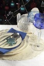 Christmas table setting in front of Christmas Tree, with blue theme crystal wine goblet glasses - vertical