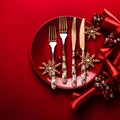 Christmas table setting with golden cutlery and Christmas decorations on red background.