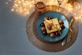 Christmas table setting. Golden decoration with gift box, glass baubles and defocused lights. Christmas and New Year holidays Royalty Free Stock Photo