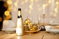 Christmas table setting with holiday decorations in a gold color. New Year celebration. A bottle and glass of champagne Royalty Free Stock Photo