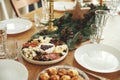 Christmas table setting. Modern cheese platter with cranberry sauce as christmas tree, fir branches and pine cones, candles,