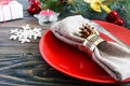 Christmas table setting. Red plate, fork, knife, candle, napkin, gifts branch of a Christmas tree Royalty Free Stock Photo