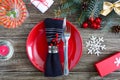 Christmas table setting. Red plate, fork, knife, martini glass, candle, napkin, gifts branch of a Christmas tree Royalty Free Stock Photo