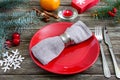 Christmas table setting. Red plate, napkin, fork, knife, branch of a tree on a wooden table Royalty Free Stock Photo