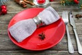 Christmas table setting. Red plate, napkin, fork, knife, branch of a tree on a wooden table. Royalty Free Stock Photo