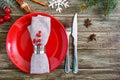 Christmas table setting. Red plate, napkin, fork, knife, branch of a tree on a wooden table Royalty Free Stock Photo