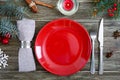 Christmas table setting. Red plate, napkin, fork, knife, branch of a tree on a wooden table Royalty Free Stock Photo