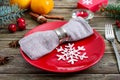 Christmas table setting. Red plate, napkin, fork, knife, branch of a tree on a wooden table Royalty Free Stock Photo