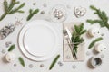 Christmas table setting with silver decorations and fir branches on gray background. Empty white plate for design. Top view, flat Royalty Free Stock Photo